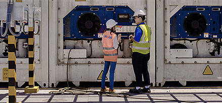 Employé Mobil et client regardant une jauge à l’extérieur d’une usine