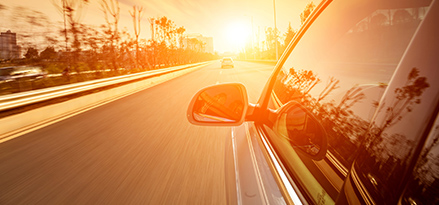 Car driving towards sunset