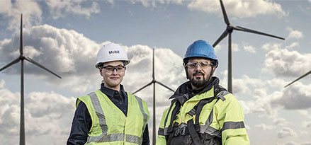 Employé Mobil et client devant des éoliennes